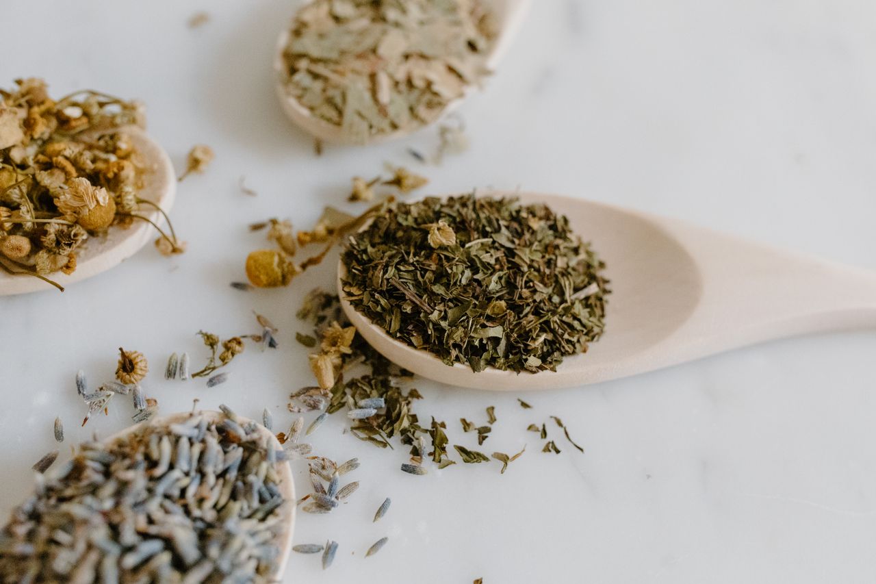 about-01 A collection of dried herbs on wooden spoons for natural remedies and alternative medicine.